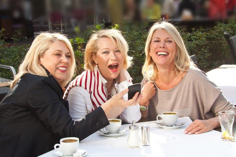 Drei lachende Freundinnen im Café